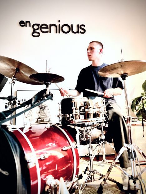 Drummer performing in front of the Engenious office logo